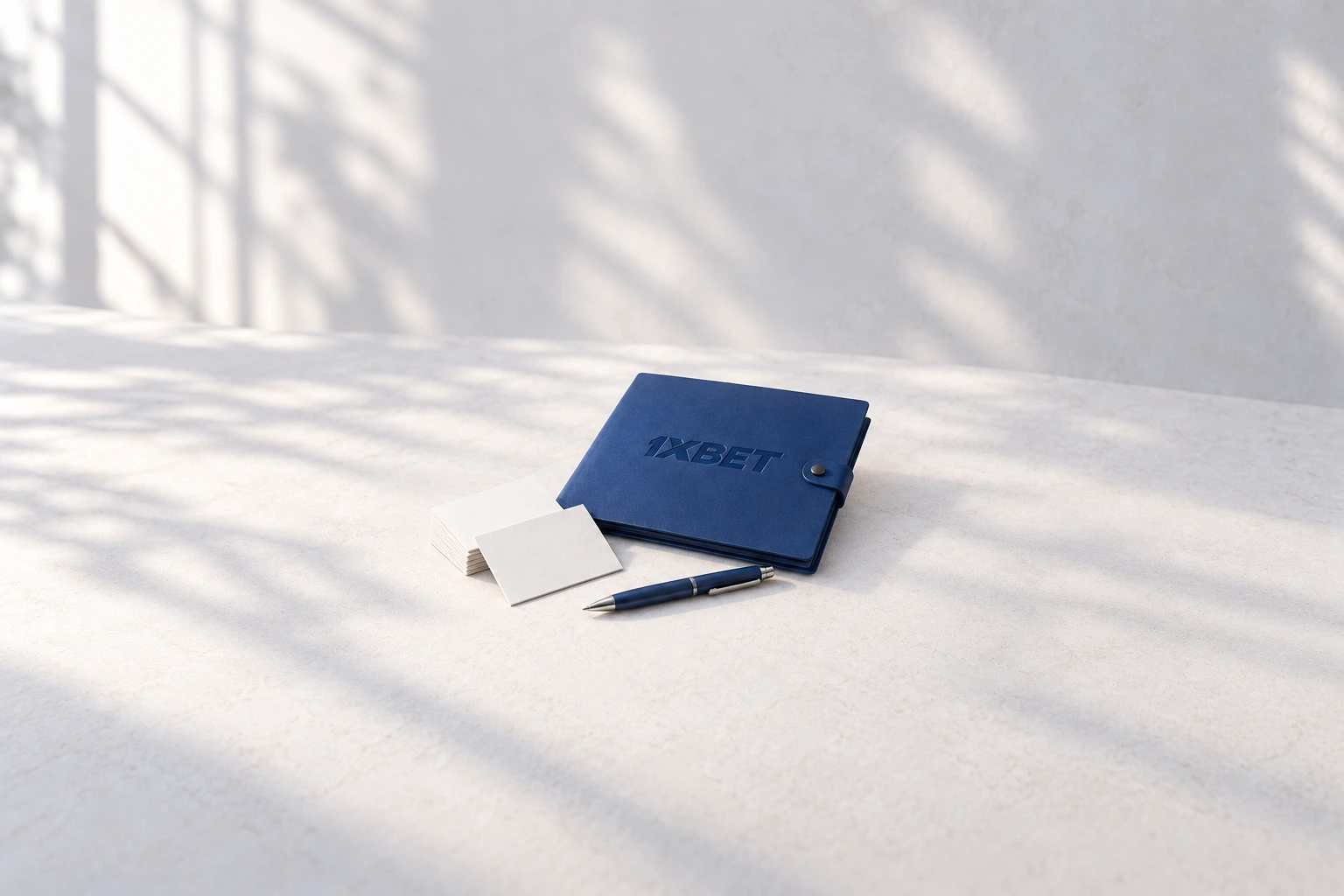 Des cartes de profil vierges et un stylo sont posés à côté d’une chemise bleue 1XBET.